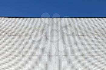Industrial building wall made of corrugated metal sheet, under blue sky