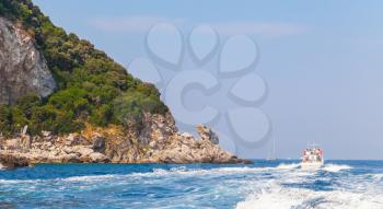 Small touristic motorboat goes near rocks of Capri island, Italy