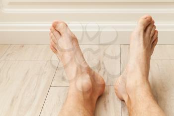 Relaxing male feet lay on wooden floor 