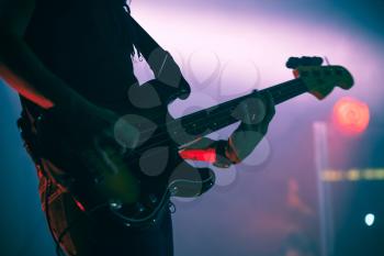 Silhouette of bass guitar player on the stage with colorful illumination, live music theme