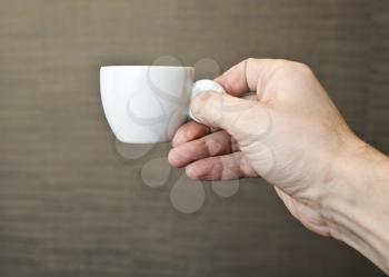 Male hand holding small espresso coffee cup