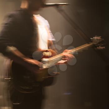 Rock and roll music background, blurred electric guitar player on a stage with motion blur effect