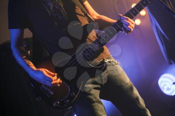 Rock music background, electric bass guitar player, closeup photo with soft selective focus