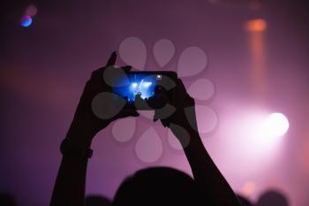Hands of woman taking photo on her smartphone camera, rock music concert