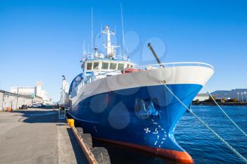 Blue and white industrial cargo ship stands moored in port of Trondheim, Norway