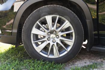 Modern unidentifiable black suv car wheel on rural roadside, closeup frontal photo
