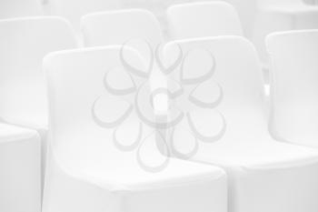 Soft white chairs stand in a row, photo with selective focus