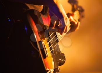 Close-up photo of bass guitar player, soft selective focus, live rock music theme