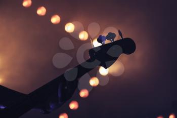 Live rock music background, electric bass guitar over bright blurred stage lights, close-up silhouette photo, soft selective focus