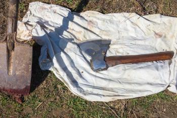 Farm tools, shovel and butcher ax lays on white fabric