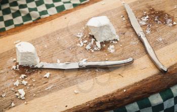 Soft farmers cheese with knives lay on wooden cutting desk, Amsterdam marketplace counters