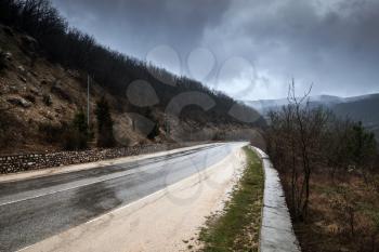 Mountain road in stormy foggy day, rainy rural landscape