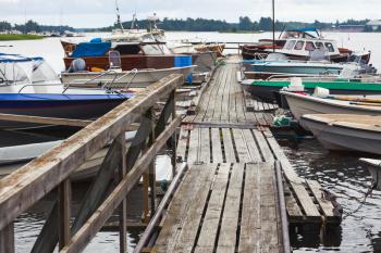 Old wooden floating pier with moored motor boats in Finland