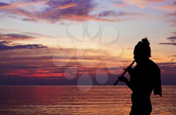 Yoga silhouette playing fluite at the sunset 