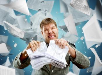 Stressed businessman tearing out stack of paper