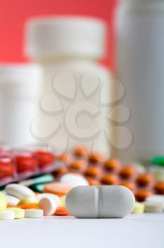 Closeup of white pill with various medicines on background