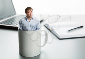 Astonished man in cup on the background of desktop