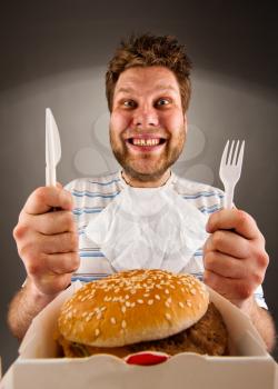 Portrait of happy man with knife and fork ready to eat burger