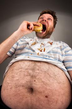 Portrait of expressive fat man eating burger