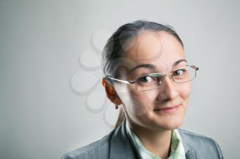Confident woman looking through her spectacles on gray background