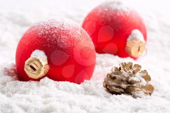 Red christmas baubles and cone on snow