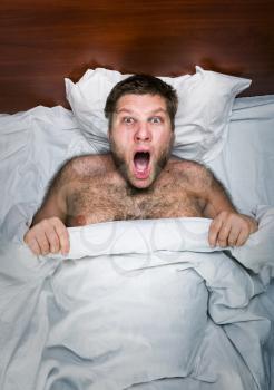 Top view of surprised man in white bed