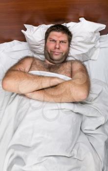 Sad man with crossed hands in white bed
