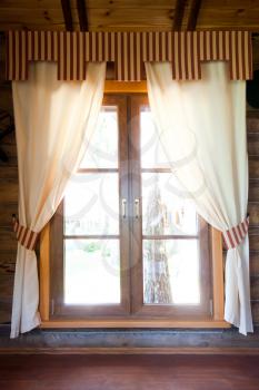 Sunlight window with curtains in wooden chalet