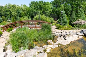 Little wooden bridge over the pond in spring green park