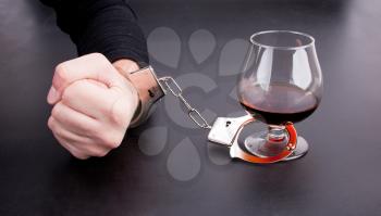 Hand locked to glass of alcohol by handcuffs