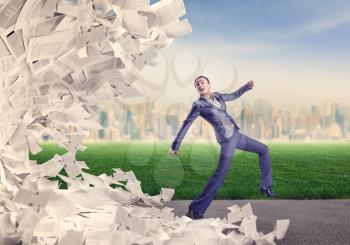 Businesswoman running from the big heap of papers