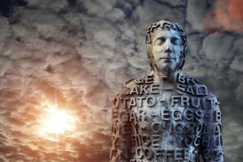 Metal human statue covered with letters against dramatic sky