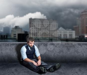 Portrait of depressed man sitting on the floor in the city
