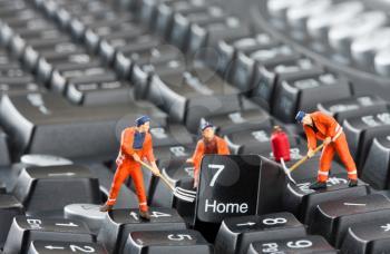 Small figurines of workers repairing computer keyboard