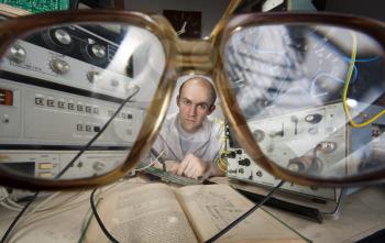 Pensive scientist working at vintage technological laboratory. View through nerd glasses