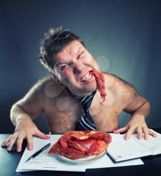 Crazy businessman eating raw meat