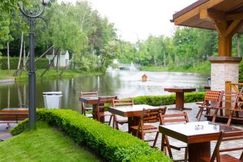 Modern restaurant with wooden furniture in the green park near the lake