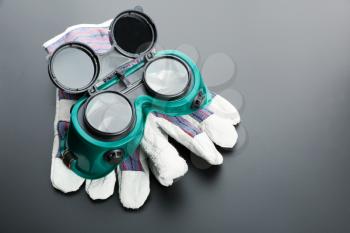 Work gloves and protective glasses on grey