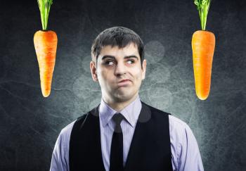 Two carrots and businessman between