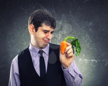 Small carrot in hand of a dissapointed man