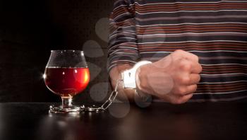 Hand locked to glass of alcohol by handcuffs