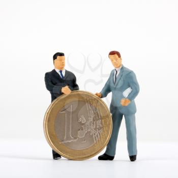 Miniature figurines of businessmen with one euro coin