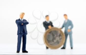 Miniature figurine of successful businessman with team on background