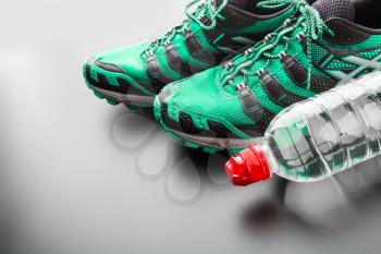 Closeup of green sports runners and a bottle of water