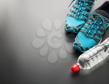 Runners and a bottle of water on grey background