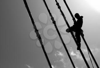 Silhouette of construction climber on suspension bridge