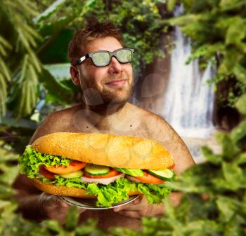 Happy man in glasses with a big sandwich against nature