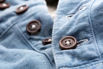 A closeup of jean cardigan with plastic buttons