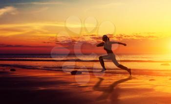 Healthy fitness woman running at sunset beach