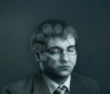 Businessman head with cracks on his face on grey background